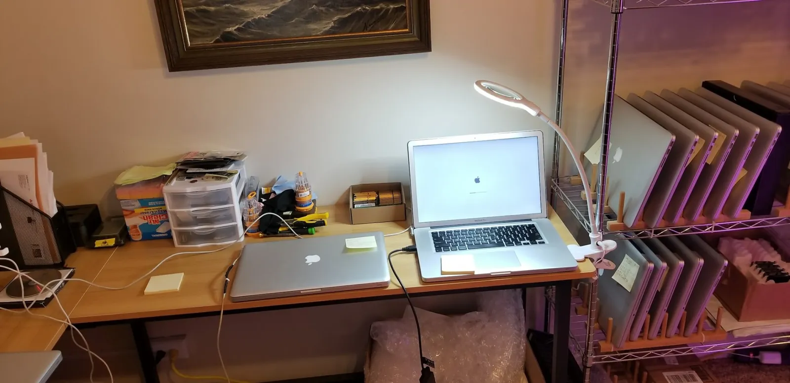 Desk with MacBooks and tools next to a rack of Macs inside the Glendale Heights duplex