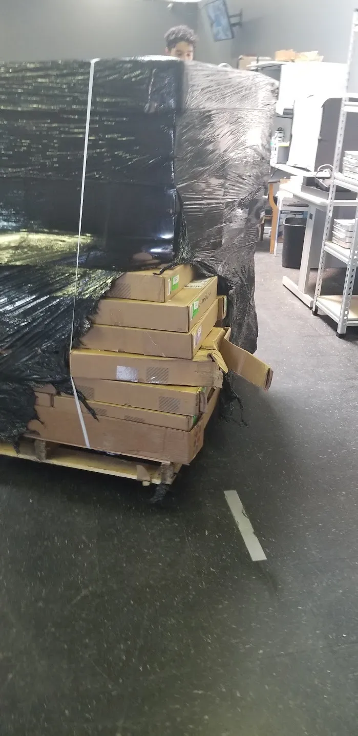 Badly damaged inbound pallet of boxes wrapped in black plastic
